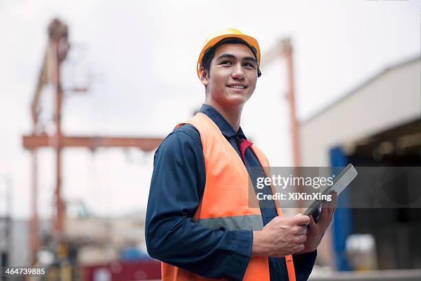 proud young worker in protective work wear in a shipping yard - scheepswerf stockfoto's en -beelden