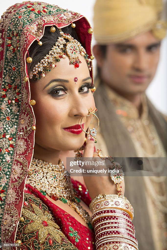 Portrait of an Indian bride posing with her husband in background