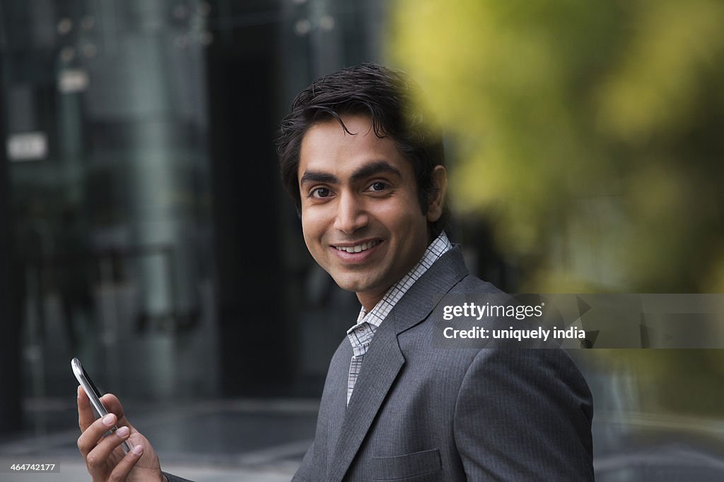 Portrait of a businessman using a mobile phone and smiling