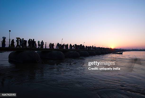 pilgrims walking over a bridge during sunrise at maha kumbh, allahabad, uttar pradesh, india - allahabad maha kumbh stock pictures, royalty-free photos & images