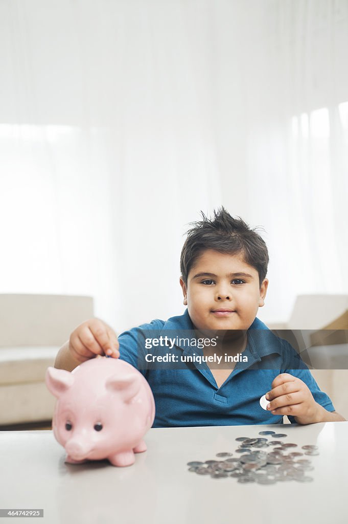 Boy inserting coin into a piggy bank