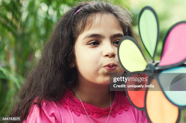 close-up of a girl blowing a pin wheel - asian pin up girls stockfoto's en -beelden