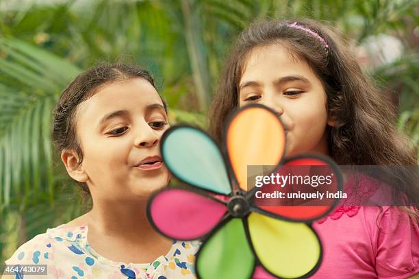 close-up of two girls blowing a pin wheel - asian pin up girls stockfoto's en -beelden