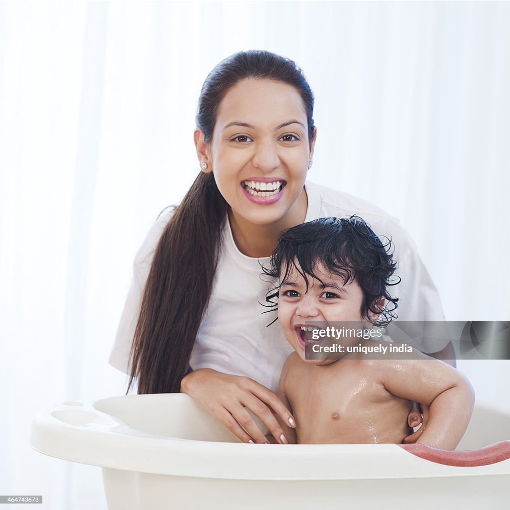 Close-up of a woman giving bath to her son and smiling