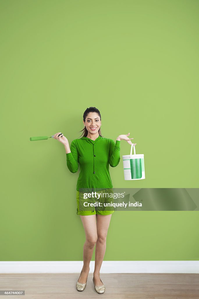Portrait of a woman holding paint roller and paint can