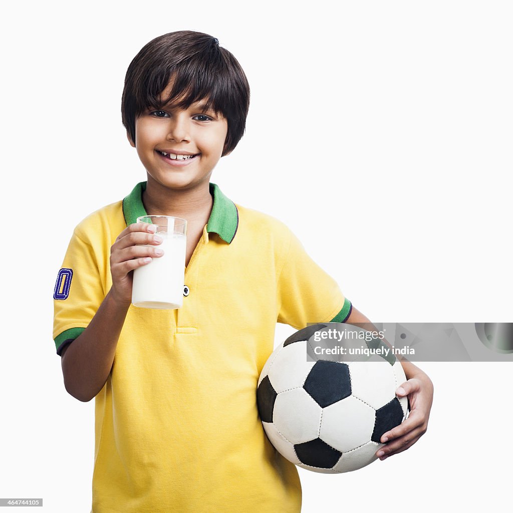 Portrait of a boy holding glass of milk and a soccer ball