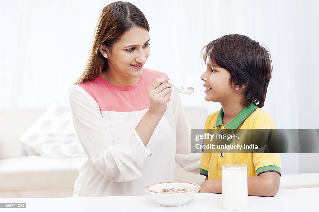 Woman feeding food to her son