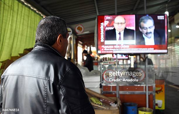 People watch on TV screen in Diyarbakir as Yalcin Akdogan gives the remarks to media after he and Interior Minister Efkan Ala met with pro-Kurdish...