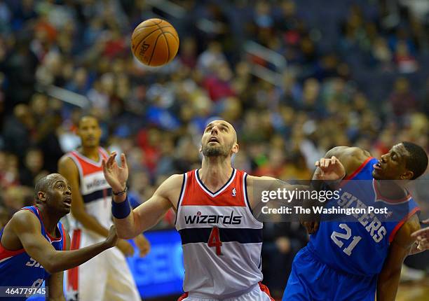 Washington center Marcin Gortat , center, slips the defense of Philadelphia shooting guard James Anderson , left, and Thaddeus Young, right, during...