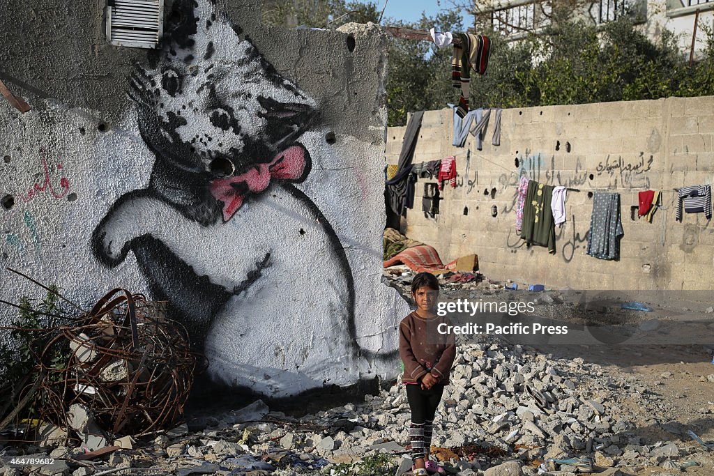 Palestinian children in front of a mural of a kitten, said...