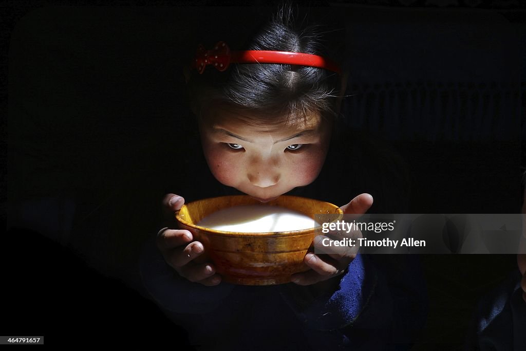 Mongolian nomadic girl drinking bowl of milk