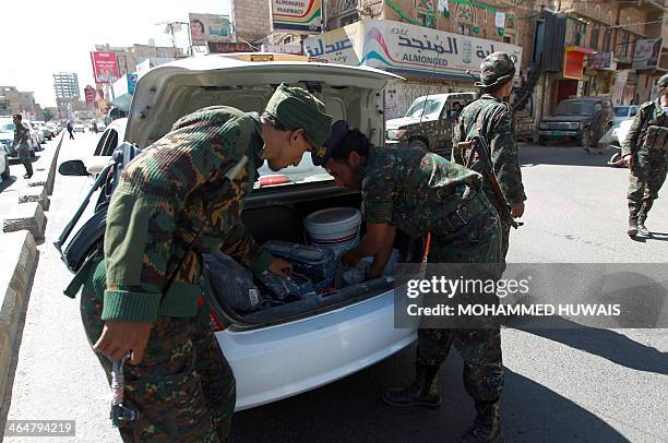 Yemeni soldiers inspect the boot of a car as they man a checkpoint in the capital Sanaa before the final closing session of the National Dialogue...