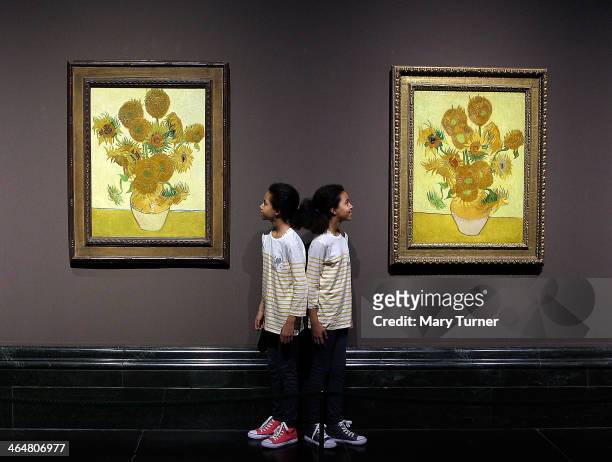 Twins Ella and Eva pose in front of two versions of Van Gogh's 'Sunflowers' which are on display in a new exhibition at the National Gallery on...