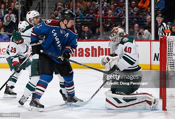 Goalie Devan Dubnyk of the Minnesota Wild makes a save and collects the puck as Cody McLeod of the Colorado Avalanche looks for a rebound against...