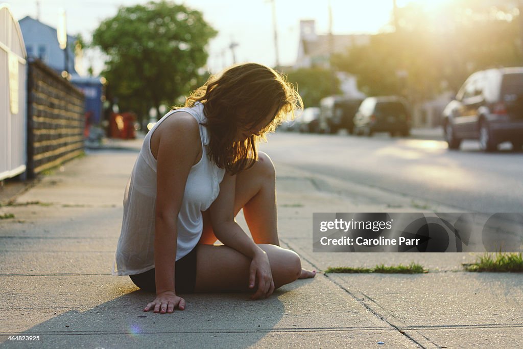 Girl Sitting on the Sidewalk at Sunset
