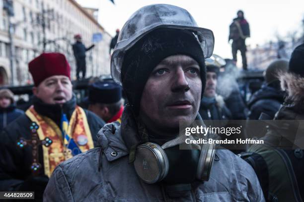 An anti-government protester, his face blackened by the smoke of burning tires, pauses as the crowd sings the Ukrainian national anthem on January...