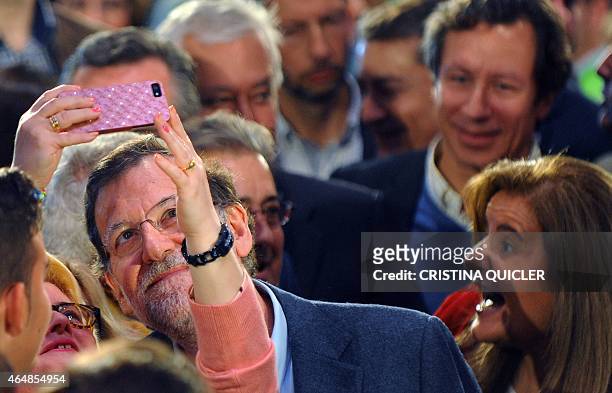 Woman takes a selfie-photo with Spanish Prime Minister and leader of ruling Popular Party Mariano Rajoy next to Spanish Minister of Employment and...