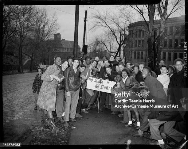 Group of young men and women with homemade placard reading 'No school if no sports,' standing outside Schenley High School, Pittsburgh, Pennsylvania,...