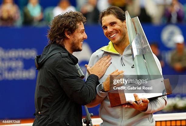 Rafael Nadal of Spain receives the trophy from former tennis player Gaston Gaudio after wining the singles final match between Rafael Nadal of Spain...