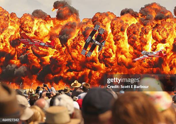 The crowd watches as stunt pilots Melissa Pemberton, Jurgis Kairys and Skip Stewart of The Immortals fly past pyrotechnics as they perform at The...