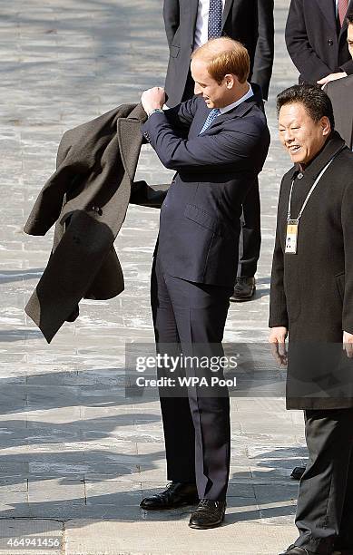 Prince William, Duke of Cambridge puts on an coat during a visit to the Forbidden City on March 2, 2015 in Beijing, China. The Duke of Cambridge is...