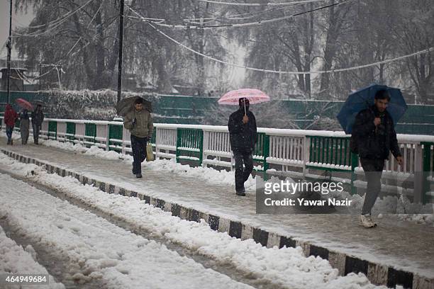 Kashmiris walk on a snow covered road amid a fresh snowfall on March 2, 2015 in Srinagar, Indian Administered Kashmir, India. Several parts of the...