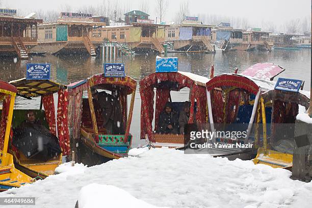 Shikara boatmen rest in their boats as they wait for tourists amid a fresh snowfall on March 2, 2015 in Srinagar, Indian Administered Kashmir, India....