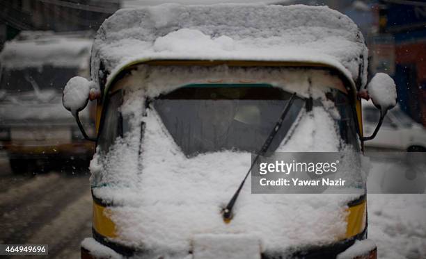 Kashmiri droves his auto rickshaw covered with snow during a fresh snowfall on March 2, 2015 in Srinagar, Indian Administered Kashmir, India. Several...