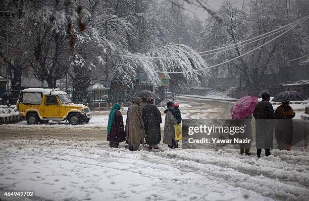 Commuters wait for transport amid a fresh snowfall on March 2, 2015 in Srinagar, Indian Administered Kashmir, India. Several parts of the Kashmir...