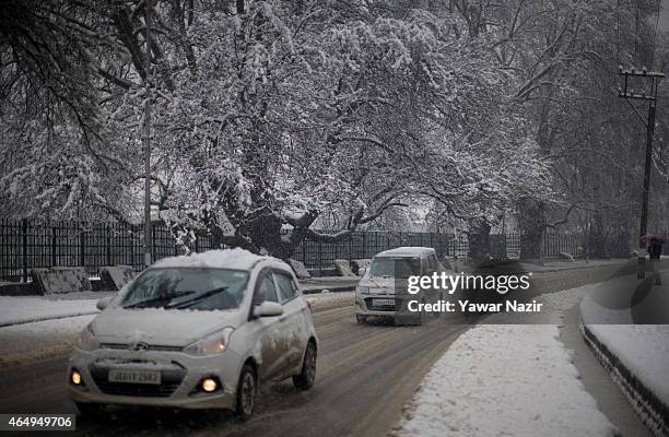 Vehicles move on a snow covered road during a fresh snowfall on March 2, 2015 in Srinagar, Indian Administered Kashmir, India. Several parts of the...