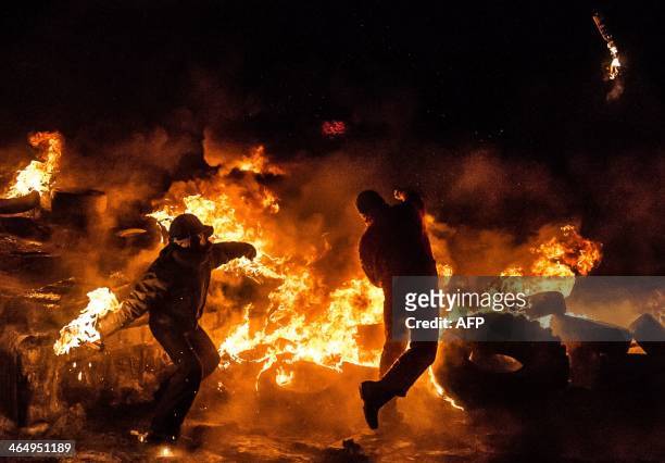 Ukrainian anti-government protesters throw Molotov cocktails during clashes with riot police in central Kiev early on January 25, 2014. Protesters...