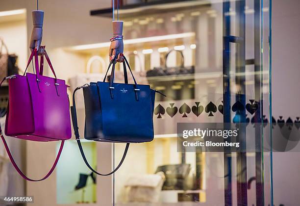 Handbags hang on display in the window of a Kate Spade & Co. Store in Corte Madera, California, U.S., on Friday, Feb. 27, 2015. Kate Spade & Co. Is...