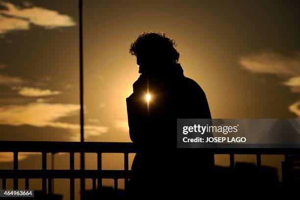 The sun sets as a visitor uses his mobile phone during the opening day of the 2015 Mobile World Congress in Barcelona on March 2, 2015. Phone makers...