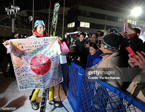 Noriaki Kasai of Japan holds a flag given by a fan with messages wishing the best in the Sochi 2014 Winter Olympics after competing in the Large Hill...