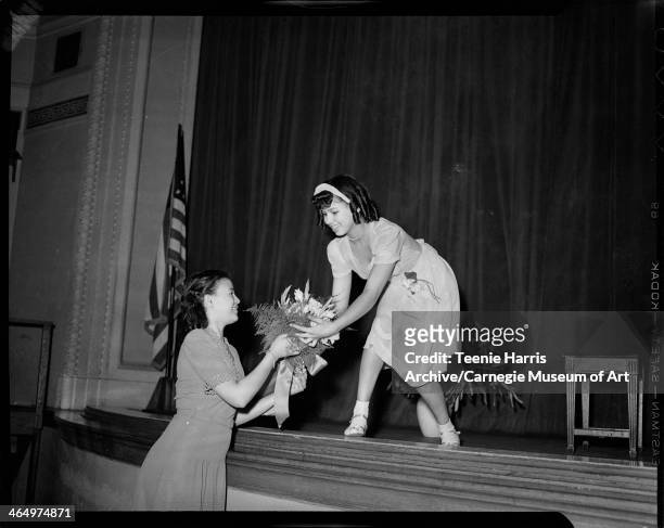 Yvonne Jackson handing bouquet of flowers to Philippa Duke Schuyler, after piano recital in Schenley High School, Pittsburgh, Pennsylvania, April...