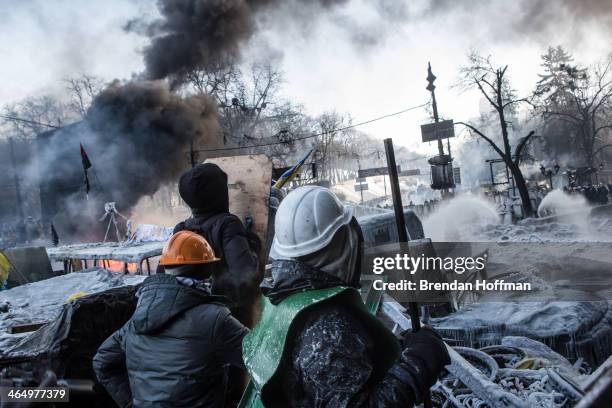 Anti-government protesters look over the barricade at police during clashes on Hrushevskoho Street near Dynamo stadium on January 25, 2014 in Kiev,...