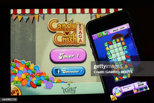 Man plays at Candy Crush Saga on his Iphone on January 25, 2014 in Rome. Candy Crush is one of the top online games developped by King.com. AFP PHOTO...