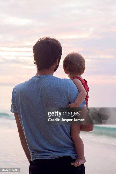 father and baby sun looking at sunrise at the beac - see the bigger picture stock pictures, royalty-free photos & images