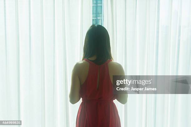 woman looking out of a window - red dress stock pictures, royalty-free photos & images