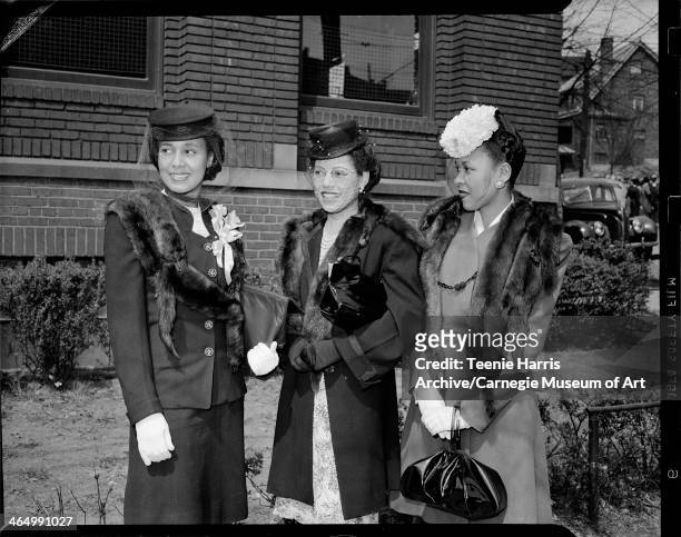 Group portrait of Edith Moore, Helen Bolden, and Dorothy Anderson Sharpe wearing mink stoles, standing in front of brick building, Pittsburgh,...