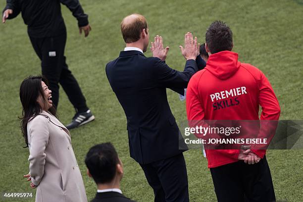 Britain's Prince William high-fives a young student during his visit to a Premier League football training camp in Shanghai on March 3, 2015. The...