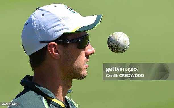 Injured Australian bowler Pat Cummins walks around the boundary during a final training session ahead of the 2015 Cricket World Cup Pool A match...