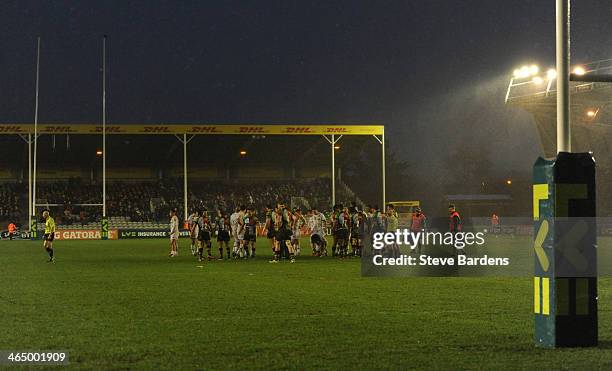 The Harlequins and Leicester Tigers players wait in the middle of the pitch after the match is abandoned on safety grounds due to a storm during the...