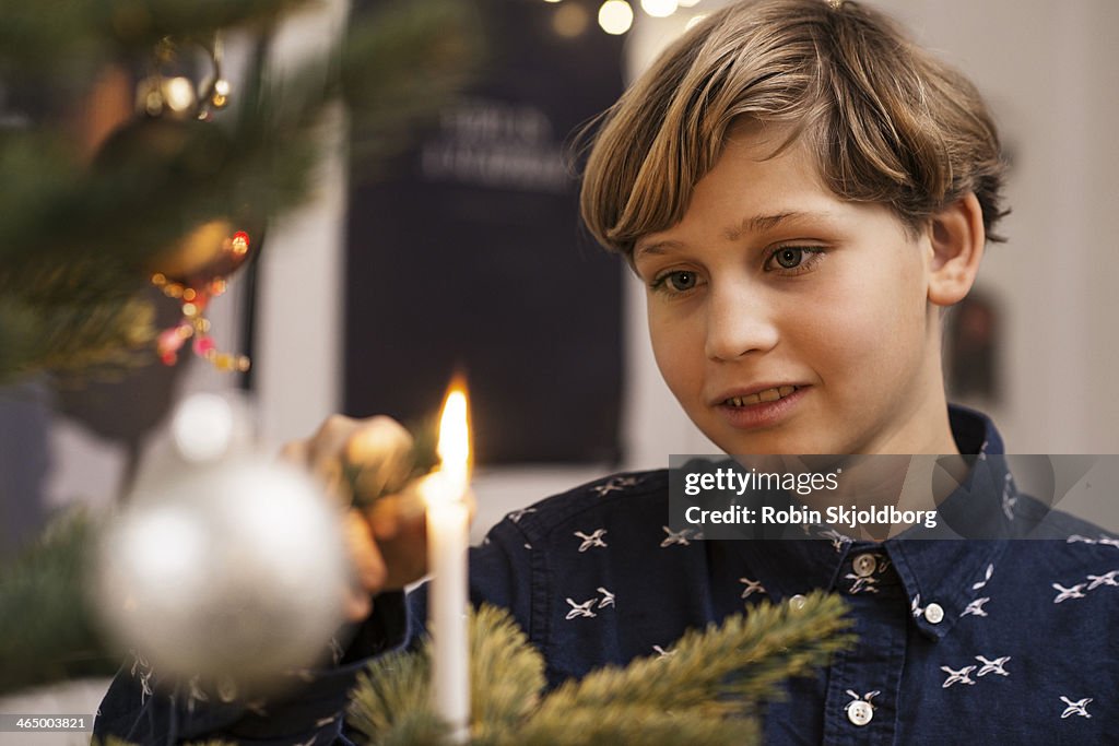 Boy lighting candle on Xmas tree