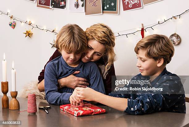 mother and sons wrapping up xmas parcel - christmas denmark stock pictures, royalty-free photos & images