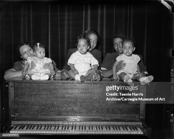 Yvonne Elizabeth Jackson, Asa Gaines Hunter, and Delilah Moten holding babies on top of upright piano, in Ammon Recreation Center for Cosmalite...
