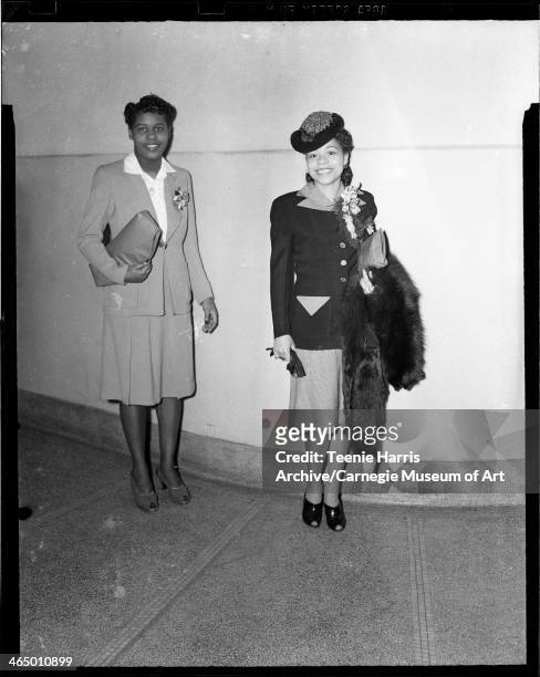 Two women, including Velma Pratt Bell holding handbag and fur, standing in Schenley High School for Beauty Shop Owners' Fashion Revue, Pittsburgh,...