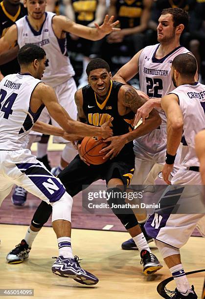 Roy Devyn Marble of the Iowa Hawkeyes is pressured by Sanjay Lumpkin, Alex Olah and Drew Crawford of the Northwestern Wildcats at Welsh-Ryan Arena on...