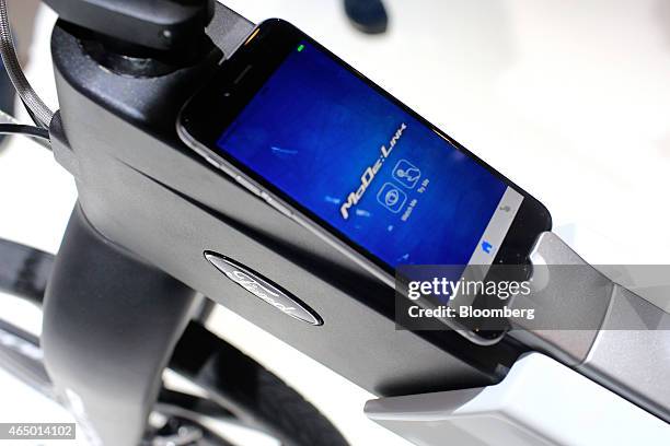 Smartphone sits in the frame of a Ford MoDe:Me foldable electric e-bike in the Ford Motor Co. Pavilion at the Mobile World Congress in Barcelona,...