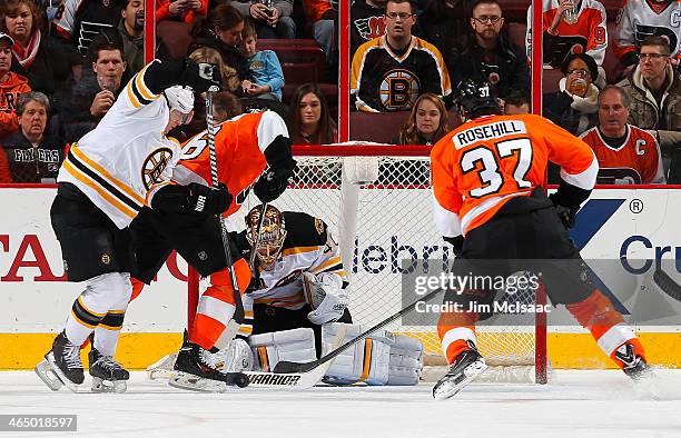 Chris VandeVelde and Jay Rosehill of the Philadelphia Flyers battle for the loose puck with goaltender Tuukka Rask and Torey Krug of the Boston...